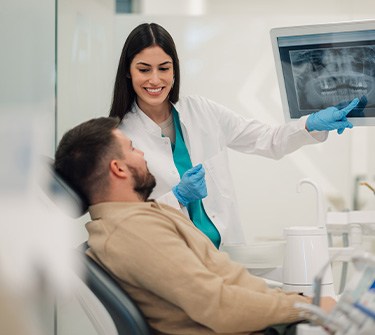 Smiling dentist showing patient X-ray