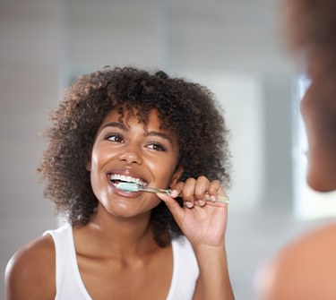 Woman smiling while brushing her teeth