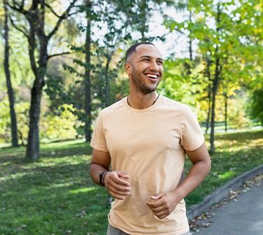 Man smiling while jogging on trail outside