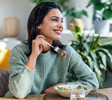 Woman smiling while eating healthy meal at home