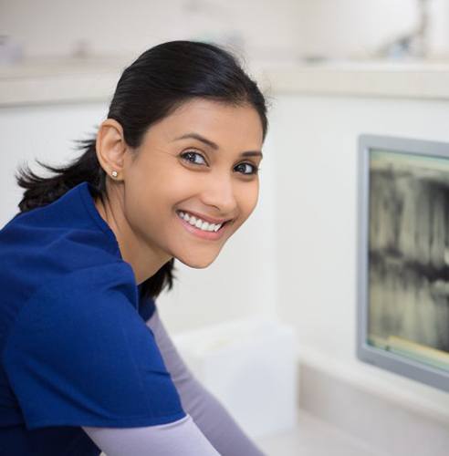 Dentist smiling and looking at patient X-rays