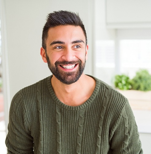 Man in green sweater smiling in kitchen