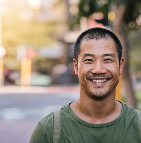 Man in green shirt walking down street and smiling